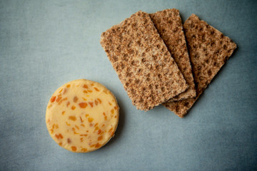 Cheese with apricots and crackers on blue background 