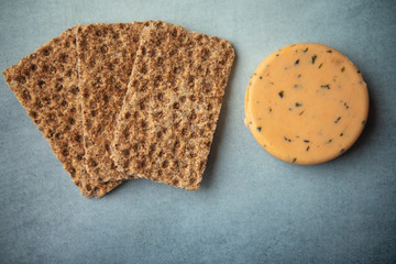 Cheese with onions,  chives and crackers on blue background 