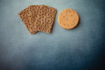 Cheese with onions,  chives and crackers on blue background 
