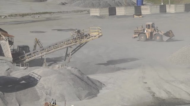 Mining industry.  Mining site conveyors of gravel in a quarry. A strong wind raises dust. 