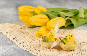 Bunch of yellow tulips and chicken-toy on a light background.