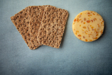 Cheese with apricots and crackers on blue background 