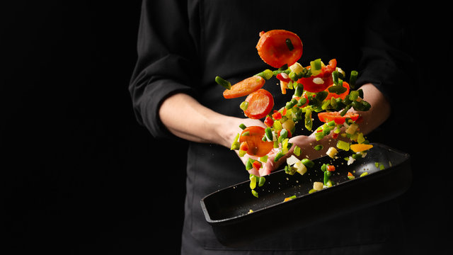 Chef prepares vegetables. freezing in motion. on black background. cooking background