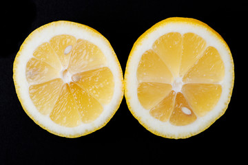 Fresh Ripe Organic Lemon cut in half isolated on black background. Citrus Limon. Rutaceae family.