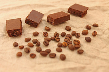 Milk porous chocolate sweets with coffee beans on a linen texture background.