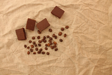 Milk porous chocolate sweets with coffee beans on a linen texture background.