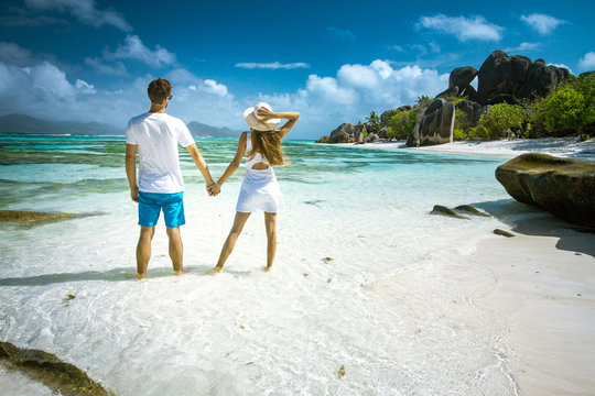 A young couple standing in shallow water on La Digue island, Seychelles