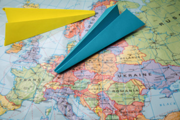 Fototapeta na wymiar Blue and yellow paper planes on blurred map background, place for copy space
