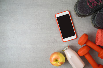 Fitness background with dumbbells, protein shake, smartphone and towel.