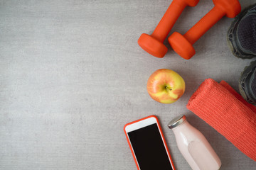 Fitness background with dumbbells, protein shake, apple and towel.