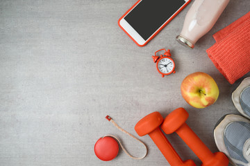Fitness background with dumbbells, protein shake, smartphone and towel.
