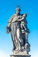 Obraz premium Statue of fat and big priest with a child at the Charles Bridge in Prague at blue sky, Czech Republic, summer time