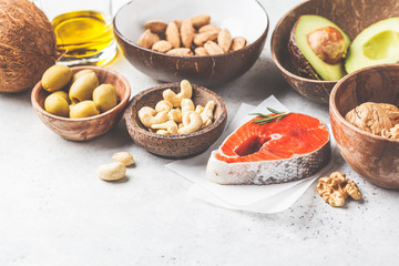 Healthy fat food background. Fish, nuts, oil, olives, avocado on white background.