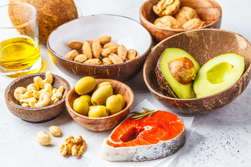 Healthy fat food background. Fish, nuts, oil, olives, avocado on white background.