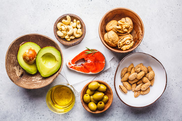 Healthy fat food background. Fish, nuts, oil, olives, avocado on white background, top view