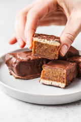 Vegan cocoa dates chocolate raw bars in hand on white background.