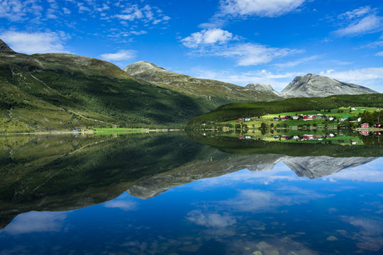 Idyllic landscape of Eidsvatnet lake near Geirangerfjord with mountains and villages reflected in the water, Sunnmore, More og Romsdal, Norway
