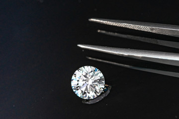 2.50 carat size diamond compared with tweezers on black reflection background