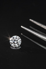 2.50 carat size diamond compared with tweezers on black reflection background