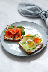 Smorrebrod - danish open sandwich with red caviar, fish, vegetables, cheese on marble background. Top view with copy space