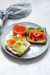 Smorrebrod - danish open sandwich with red caviar, fish, vegetables, cheese on marble background. Top view with copy space
