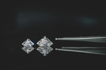 1.00 carat size and 2.50 carat size bottom up diamonds with tweezers on black background