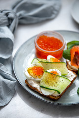 Smorrebrod - danish open sandwich with red caviar, fish, vegetables, cheese on marble background. Top view with copy space