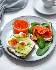 Smorrebrod - danish open sandwich with red caviar, fish, vegetables, cheese on marble background. Top view with copy space