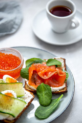 Smorrebrod - danish open sandwich with red caviar, fish, vegetables, cheese on marble background. Top view with copy space