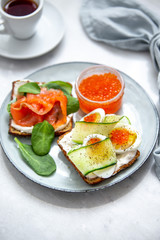 Smorrebrod - danish open sandwich with red caviar, fish, vegetables, cheese on marble background. Top view with copy space