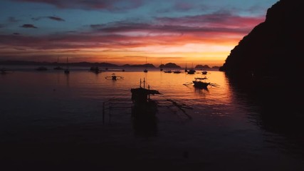 Aerial view of boats and yachts in the tropical bay on the sunset. El Nido, Palawan, Philippines. Marine tropical sunset over the sea. Travel concept.