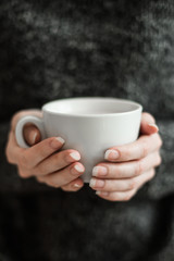 Woman in a cozy room with a cup of cocoa in her hand.