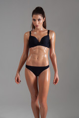 Fitness dancer and fashion model woman in bikini. Female with wet skin in lingerie posing in studio.