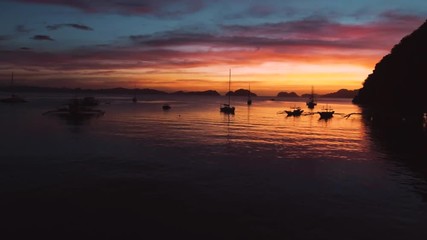 Aerial view of boats and yachts in the tropical bay on the sunset. El Nido, Palawan, Philippines. Marine tropical sunset over the sea. Travel concept.