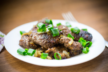 fried liver with onions in a plate on a wooden