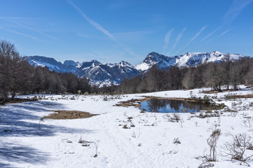 Fototapeta premium Photograph of the top of the valley full of snow with the snowy mountains in the background in the area of Picos de Europa de Leon, Spain.