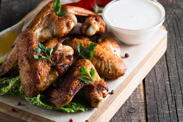 Close-up photo of bbq chicken wings with fries and beer. Barbeques meat with sauces, ketchup, mayonnaise. Fast and junk food concept. 
