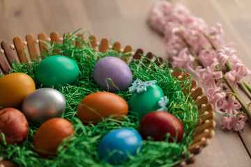 Fototapeta na wymiar Colorful easter eggs in basket with flowers