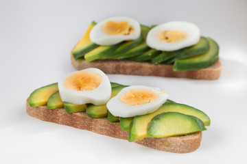 Sandwich with avocado and egg on a wooden background