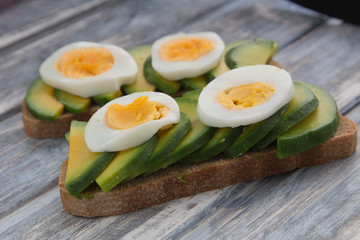 Sandwich with avocado and egg on a wooden background