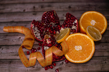 Diet and healthy lifestyle concept. Fruit pomegranate, orange, lemon and measuring tape close-up.