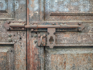 Old metal bolt on the wooden door background.