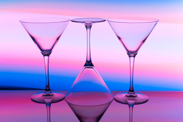 Three cocktail / martini glasses in a row with colorful streaks of light painting behind