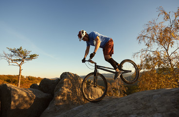 Athletic cyclist riding on front wheel on trial bike. professional Sportsman rider making acrobatic...