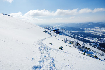 Footprints in the snow lead down the hill