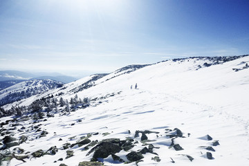 Two people climb a hill in winter