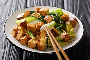 Dietary fried tofu with baby bok choy, soy sauce and sesame seeds closeup on a plate on the table. horizontal