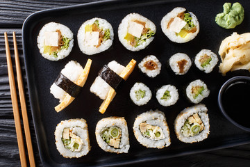 Japanese rolls Hosomaki, Uramaki, Maki, Nigiri, Tamagoyaki with various fillings close-up on a plate. Horizontal top view