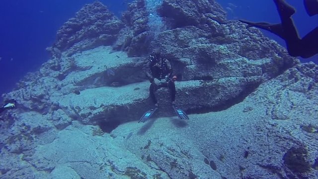 Dive Guide Sitting On Rock Ledge
