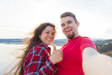 Travel, tourism and vacation concept - Happy married couple taking selfie near a sea